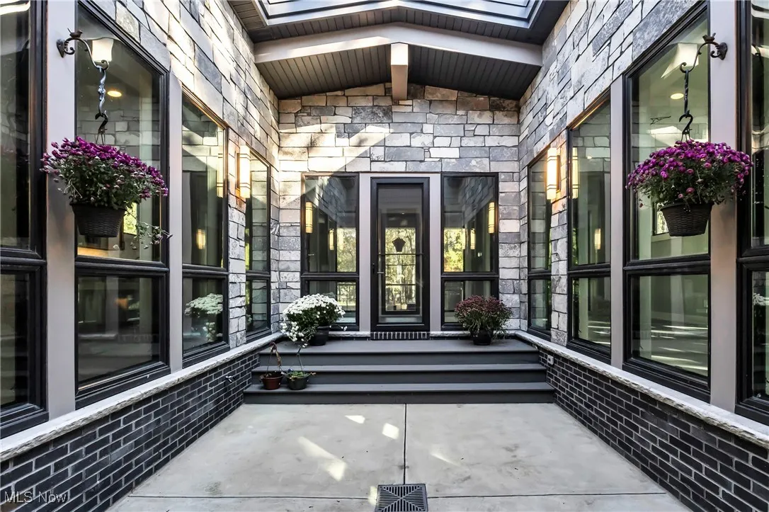Doorway to property featuring stone siding and a patio area