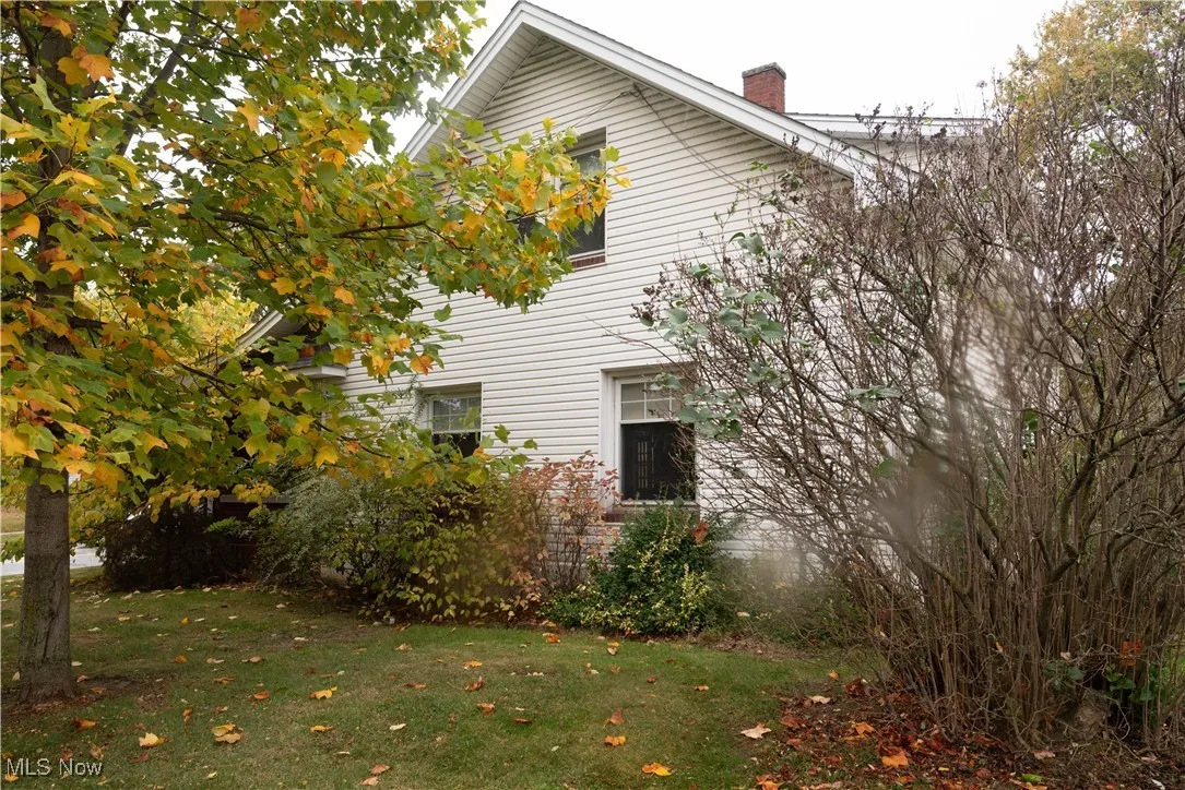 View of side of property with a yard and a chimney