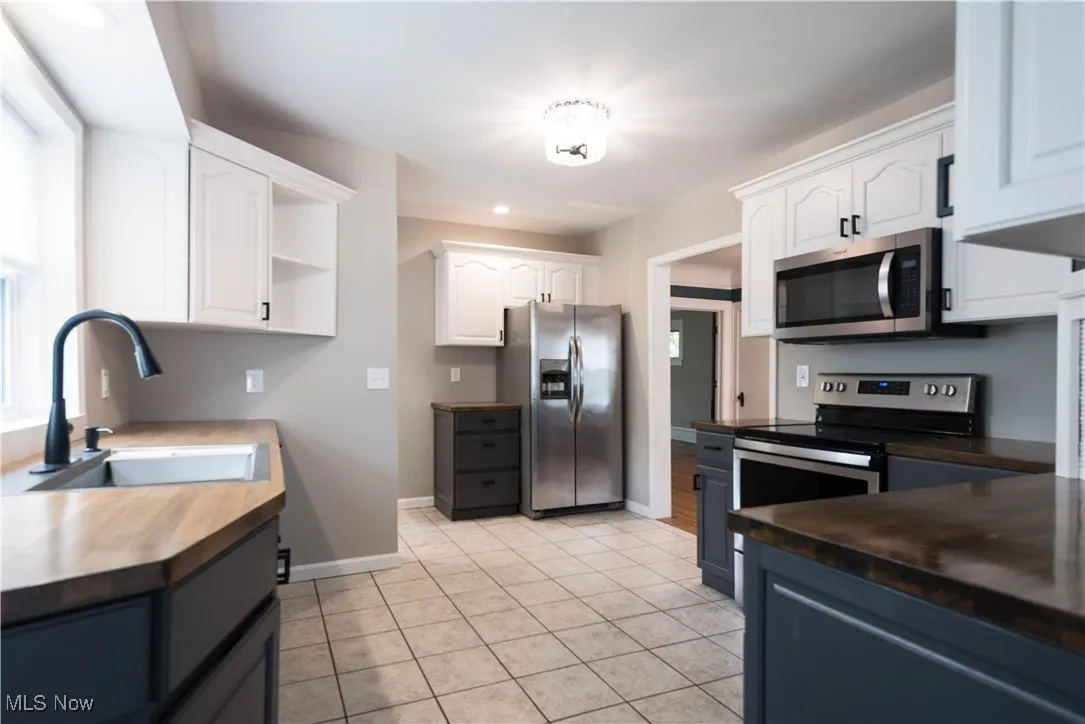 Kitchen featuring white cabinetry, open shelves, stainless steel appliances, light tile patterned floors, and recessed lighting