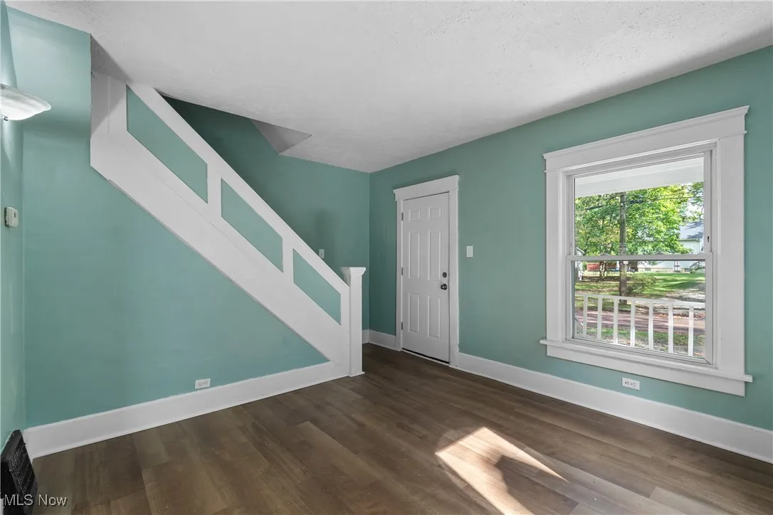 Entryway with dark wood-type flooring, a textured ceiling, and stairway