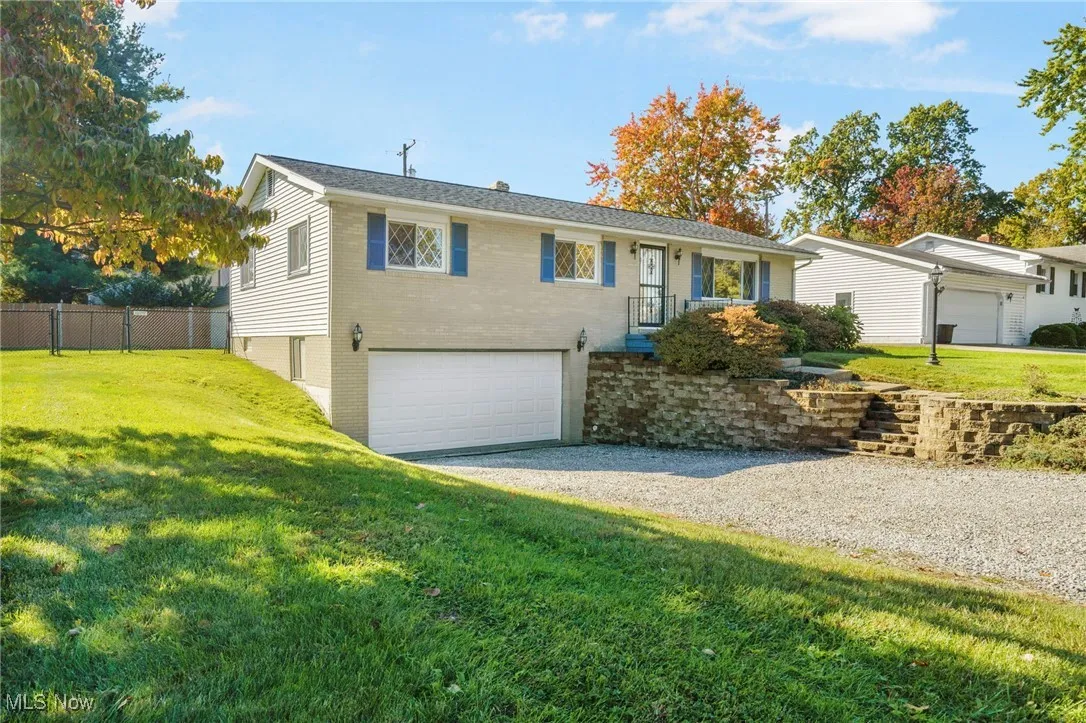 Ranch-style home featuring gravel driveway, an attached garage, and brick/vinyl siding