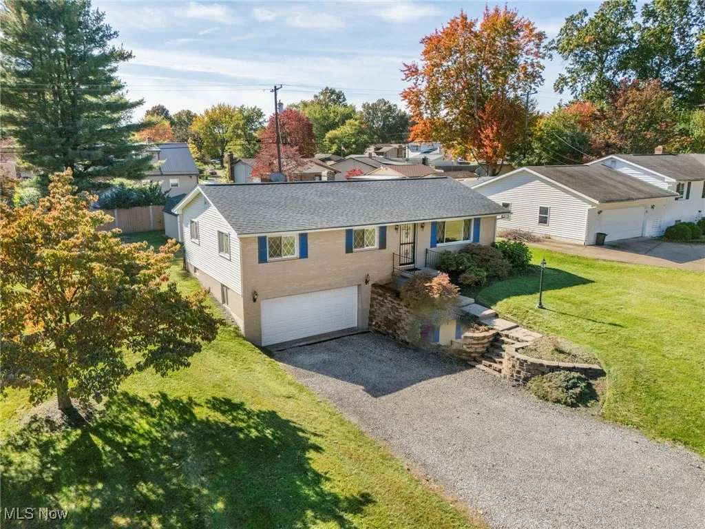 Single story home featuring a front yard, driveway, roof with shingles, an attached garage, and brick/vinyl siding