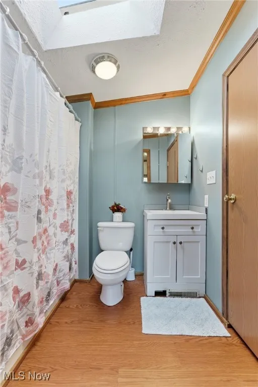 Bathroom with crown molding, a shower with curtain, light wood-style floors, vanity, and a textured ceiling