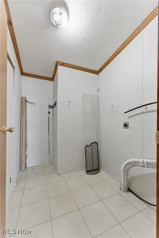 Bathroom featuring crown molding, light tile patterned floors, and a textured ceiling