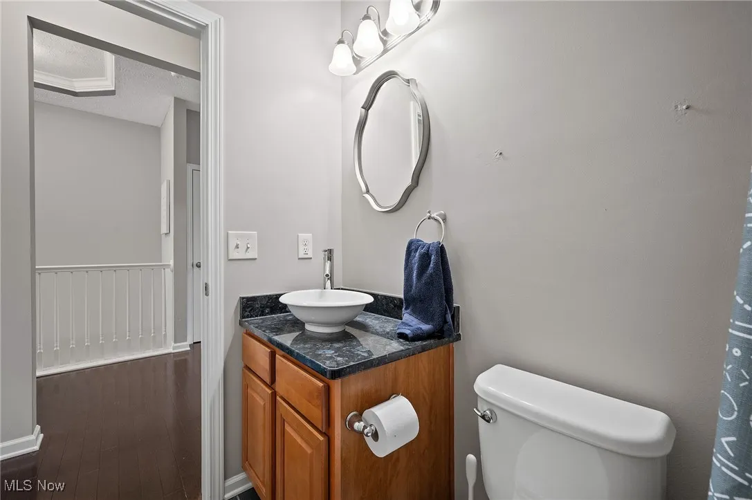 Full bathroom with vanity, curtained shower, a textured ceiling, and dark wood-style flooring