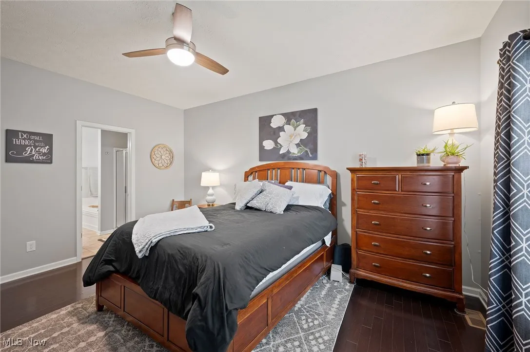 Bedroom featuring dark wood finished floors, a ceiling fan, and ensuite bath