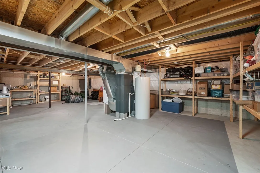 Unfinished basement featuring heating unit and water heater