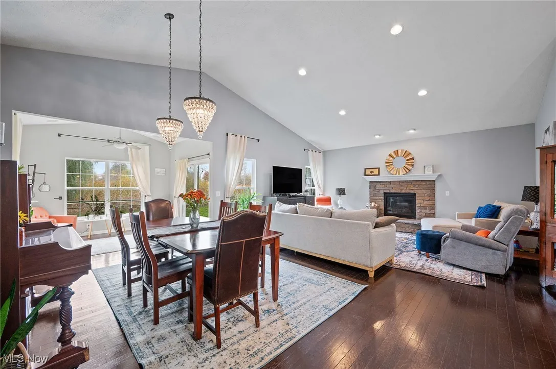 Dining area featuring a fireplace, dark wood finished floors, high vaulted ceiling, healthy amount of natural light, and recessed lighting