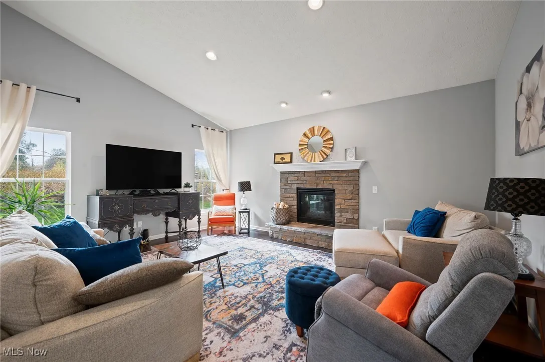 Living area with a stone fireplace, recessed lighting, and high vaulted ceiling