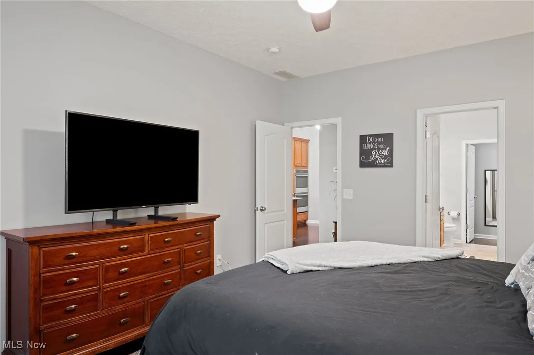 Bedroom featuring ceiling fan and ensuite bath