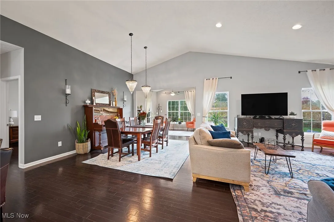 Living room featuring high vaulted ceiling, dark wood-style floors, and ceiling fan