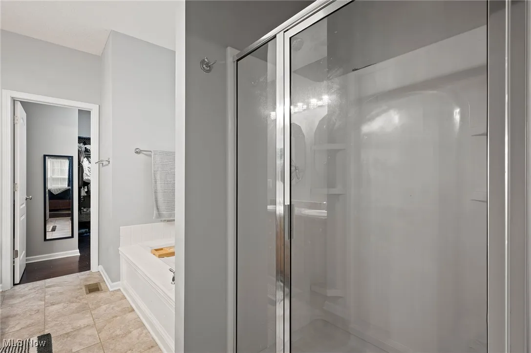 Ensuite bathroom with a bath, a stall shower, and light tile patterned floors