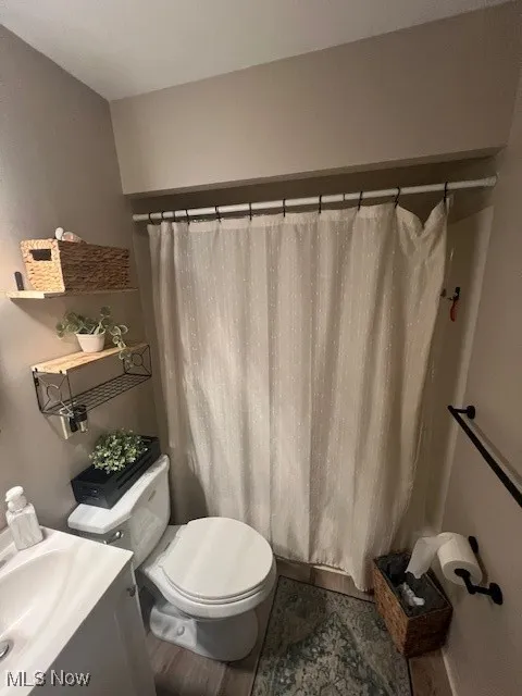 Bathroom with a shower with shower curtain, wood finished floors, and vanity
