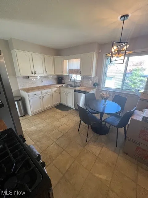 Kitchen with backsplash, pendant lighting, light countertops, and white cabinets