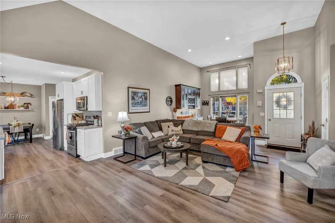 Living area with a chandelier, a towering ceiling, recessed lighting, and light wood finished floors