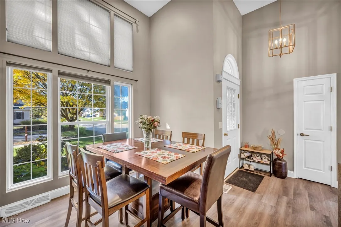 Dining space with a towering ceiling, healthy amount of natural light, light wood-style floors, and a chandelier