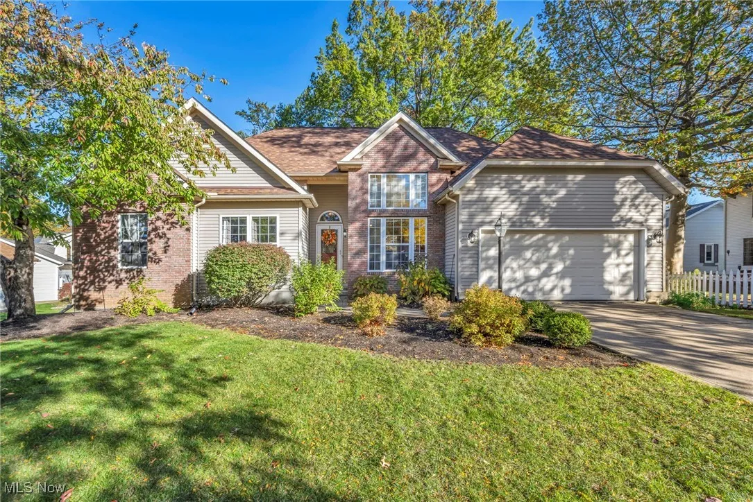Traditional-style home featuring brick siding, driveway, and an attached garage