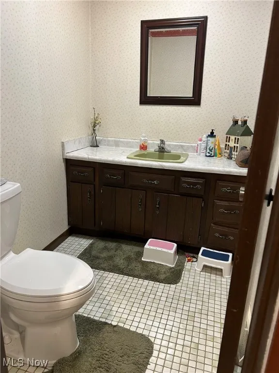 Bathroom with vanity, light tile patterned floors, and wallpapered walls