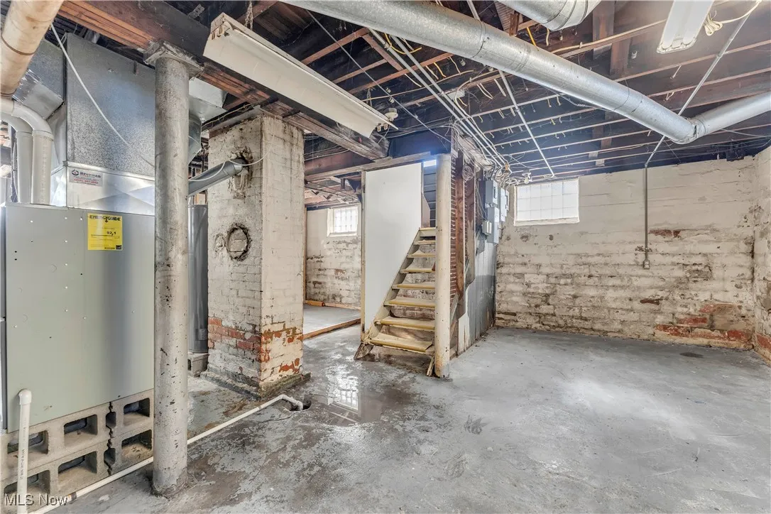 Basement featuring heating unit and stairway