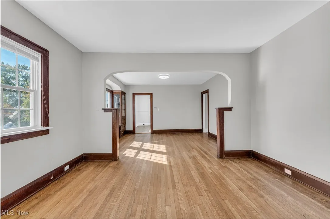 Empty room featuring light wood-type flooring, plenty of natural light, and arched walkways