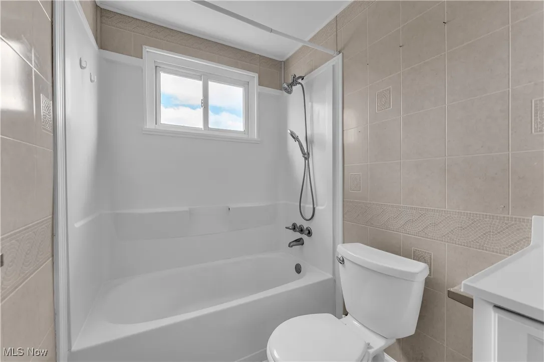 Bathroom featuring tile walls, vanity, and shower / bath combination