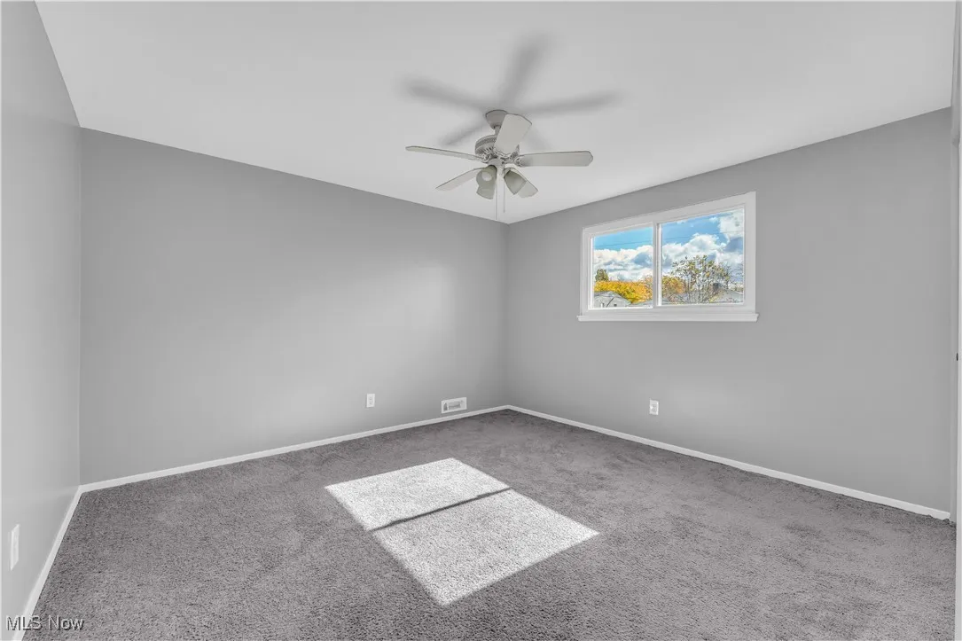 Carpeted empty room featuring baseboards and a ceiling fan