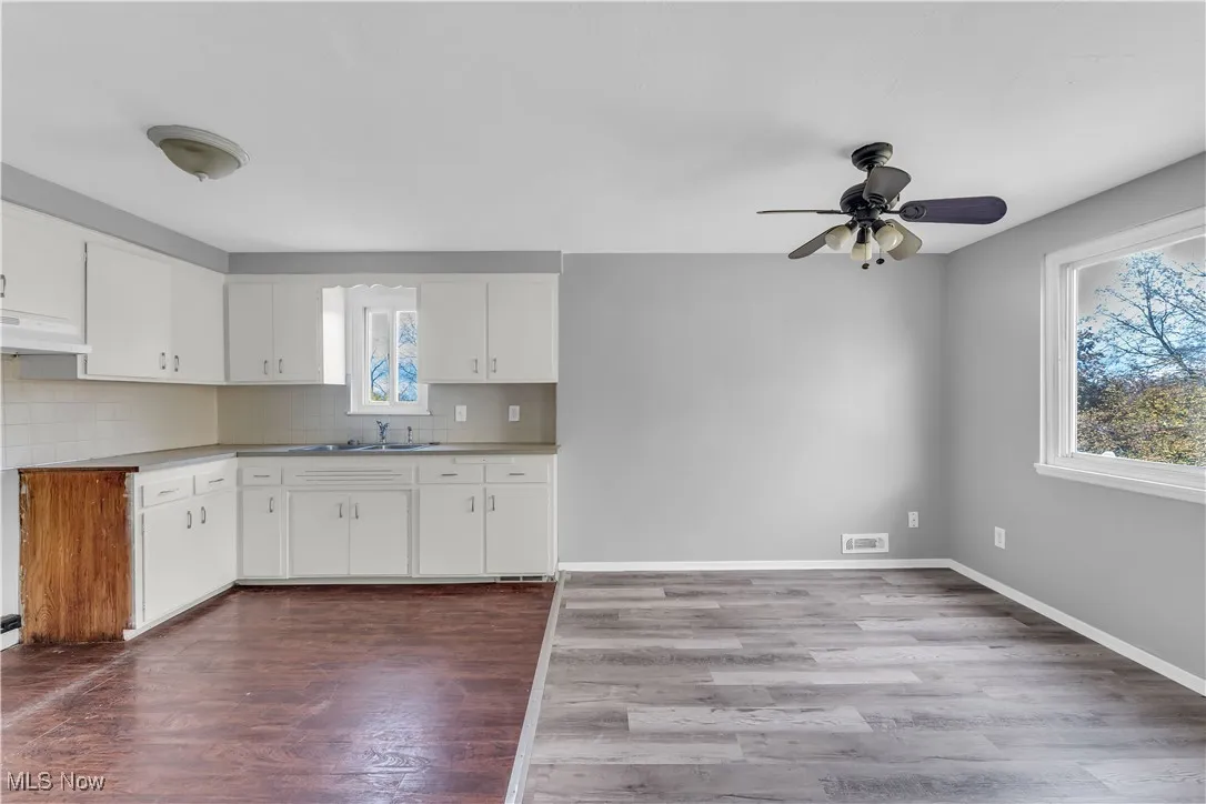 Kitchen featuring dark wood-type flooring, tasteful backsplash, white cabinetry, and ceiling fan