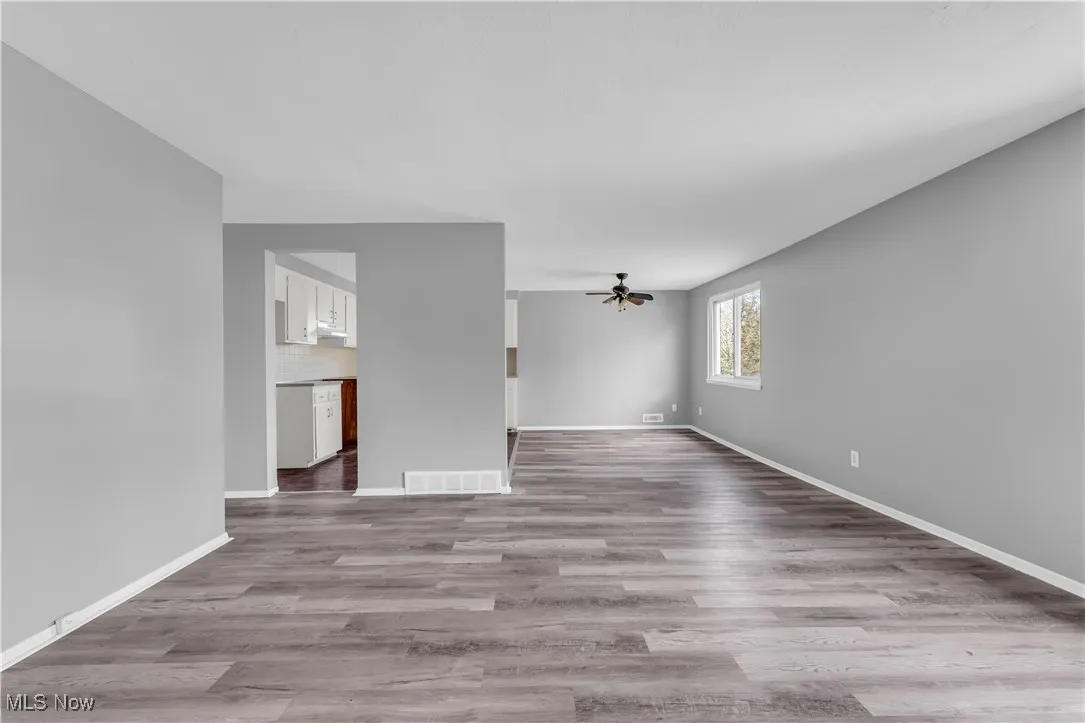Unfurnished living room with light wood-style flooring and ceiling fan