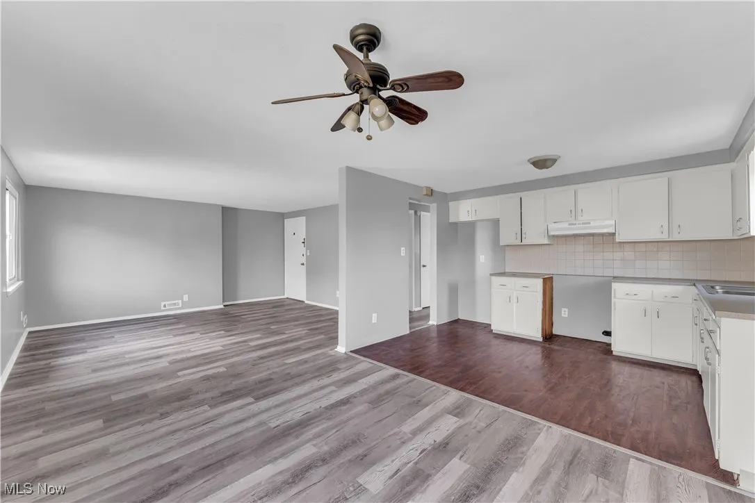 Kitchen featuring tasteful backsplash, white cabinets, dark wood-style floors, and a ceiling fan