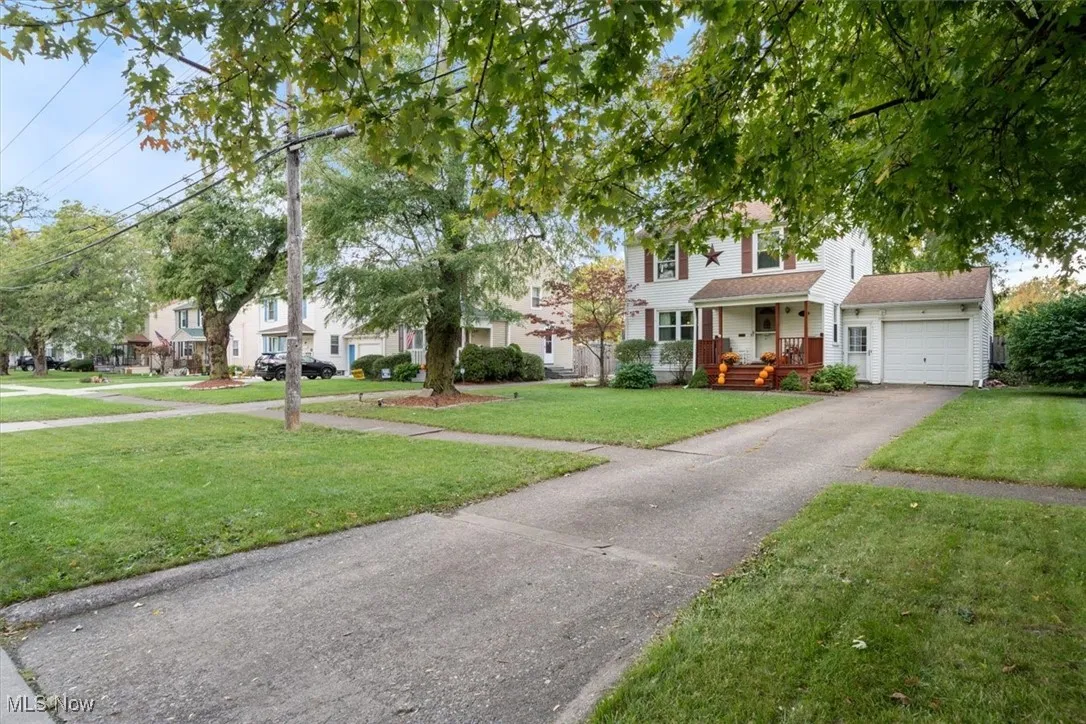 View of front facade with covered porch, a front lawn, driveway, an attached garage, and a residential view