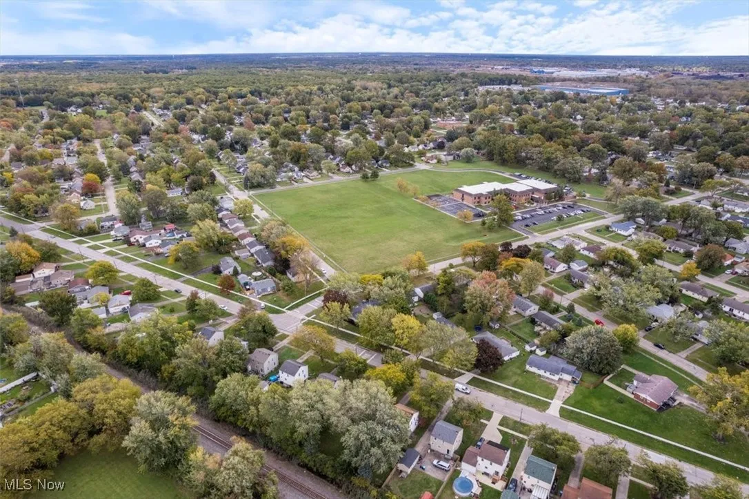 Aerial view of property's location featuring nearby suburban area and a tree filled landscape