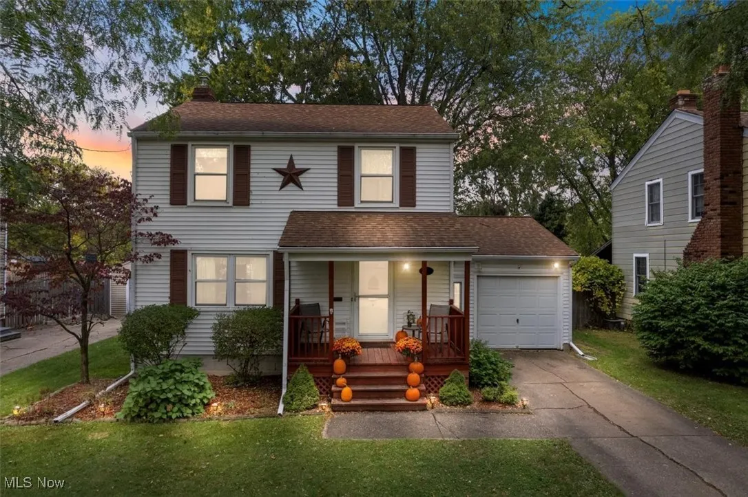 View of front of property featuring a porch, concrete driveway, a chimney, and a front lawn