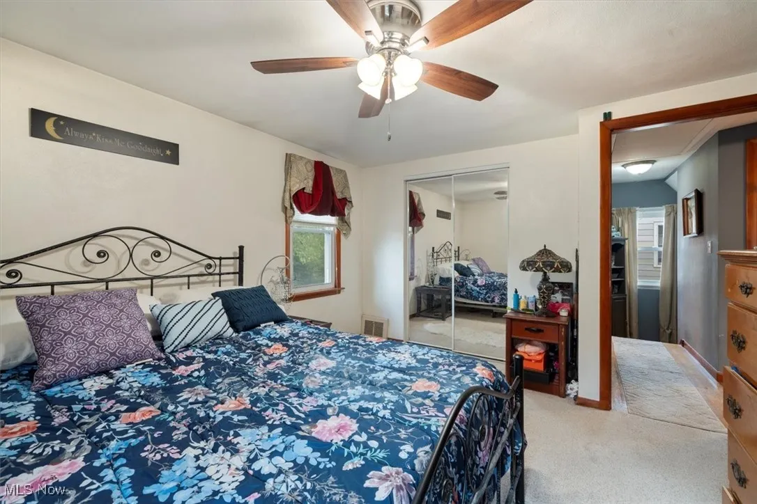 Carpeted bedroom featuring a ceiling fan and a closet