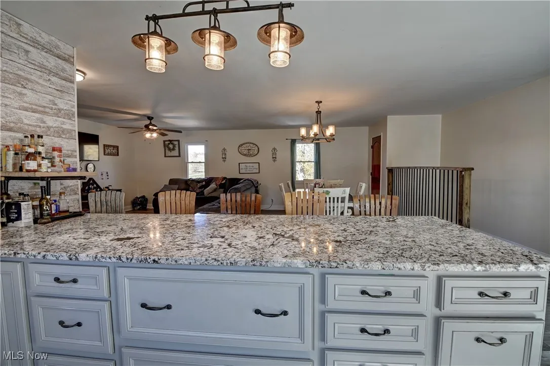 Kitchen with light stone countertops, pendant lighting, a chandelier, and open floor plan
