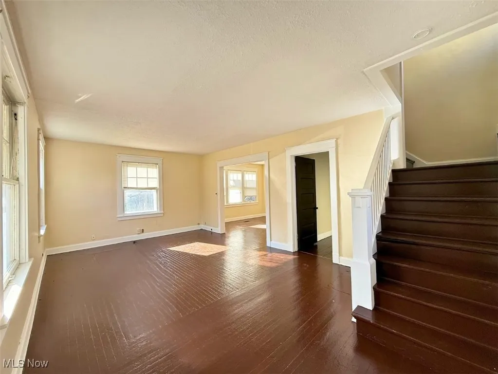 FH-Unfurnished living room featuring stairs, a textured ceiling, and dark wood-style flooring