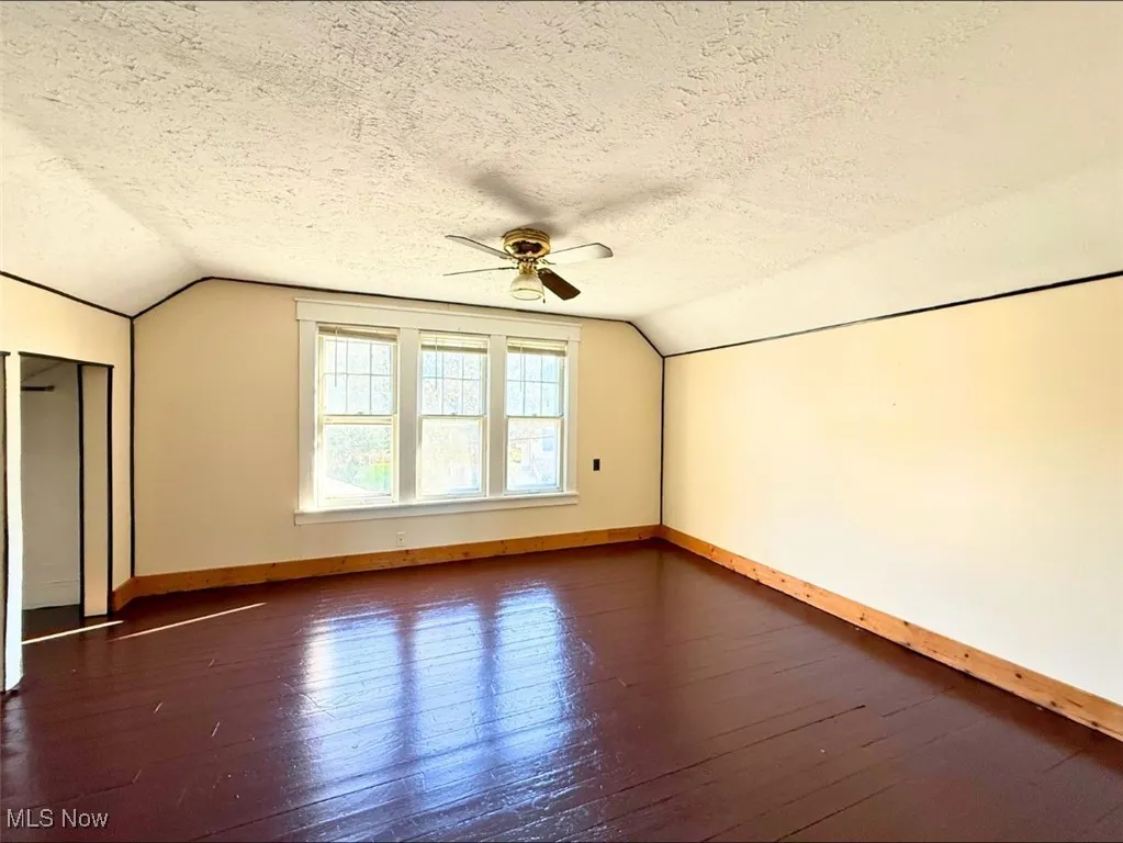 FH-MST BEDroom with vaulted ceiling, dark wood-style flooring, a textured ceiling, and a ceiling fan