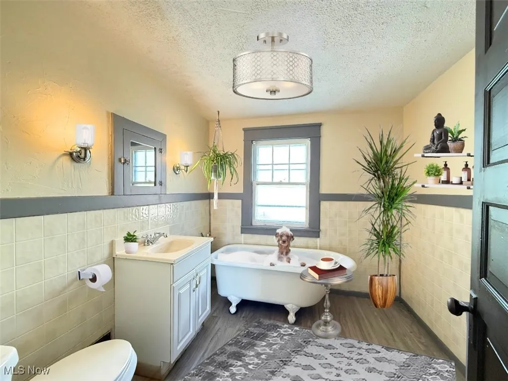 FH-2ND FL FULL Bathroom featuring tile walls, a textured ceiling, a wainscoted wall, dark wood-style floors, and a soaking tub