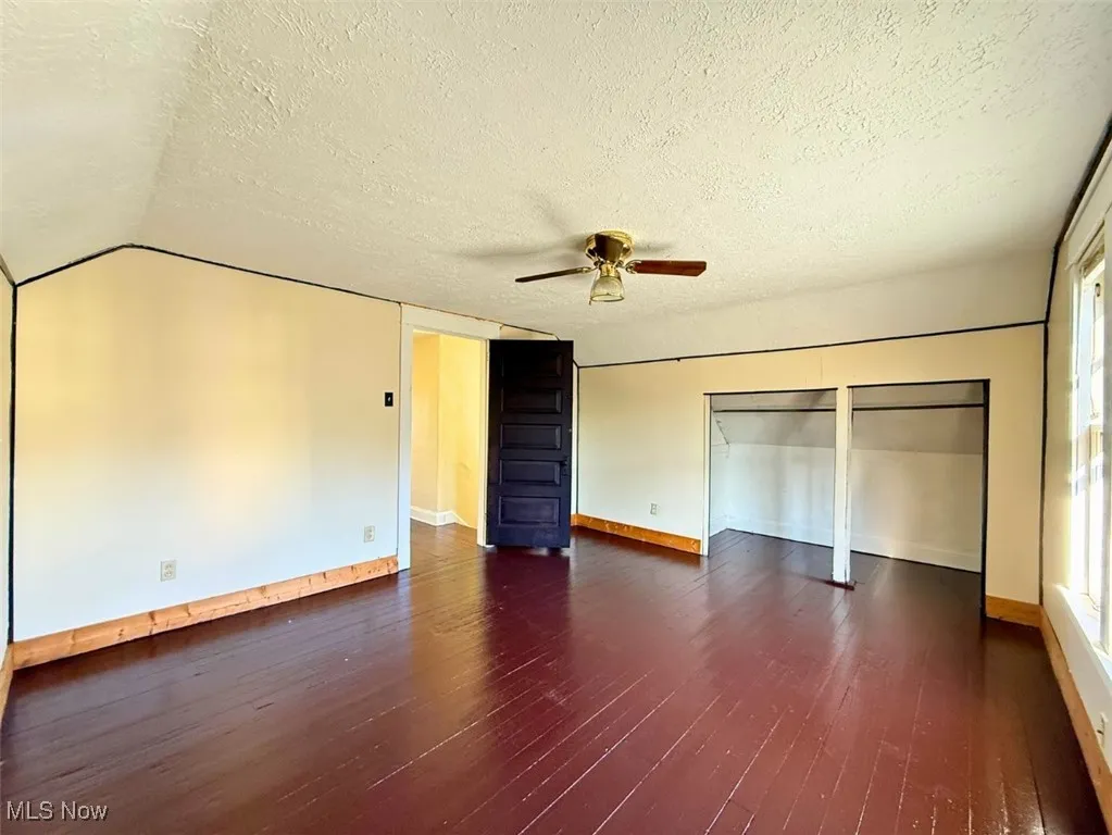 FH-MST BED Unfurnished bedroom featuring dark wood-style floors, a textured ceiling, a closet, and ceiling fan
