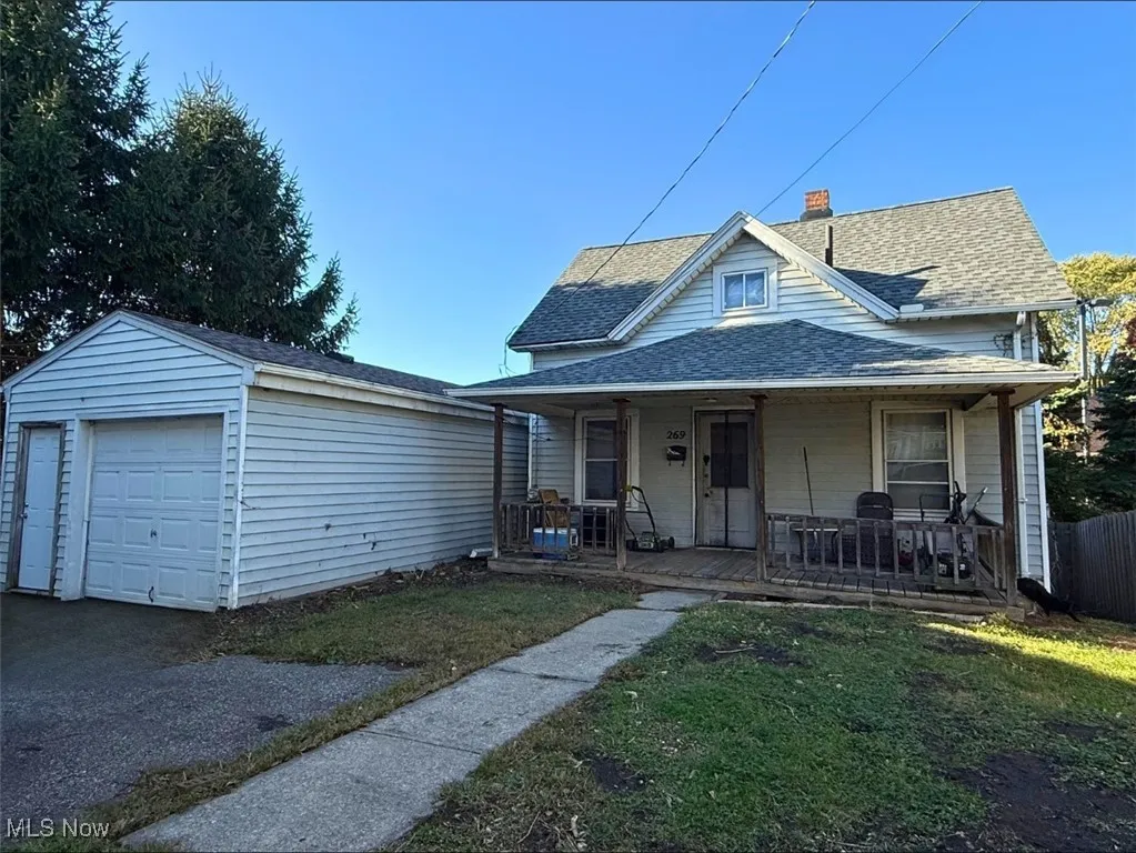 BACK HOUSE-View of front of home with a garage, roof with shingles, a porch, a chimney, and an outbuilding