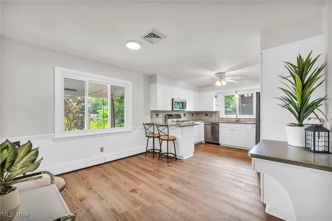 Kitchen featuring light wood-style flooring, white cabinetry, a kitchen bar, and a peninsula