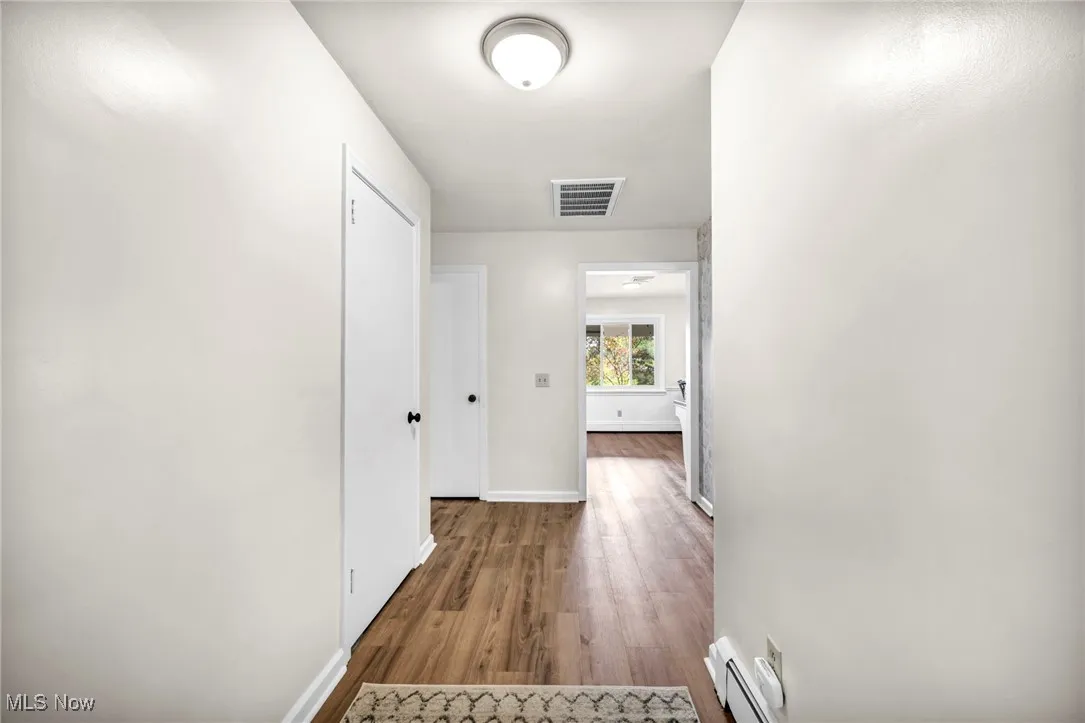 Corridor featuring wood finished floors and a baseboard heating unit