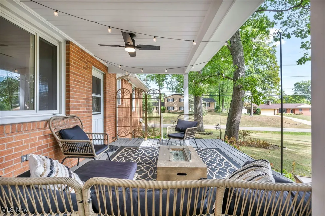 Porch with an outdoor living space with a fire pit, a ceiling fan, and a residential view