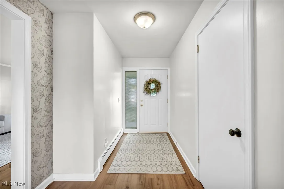 Foyer featuring a baseboard heating unit and wood finished floors
