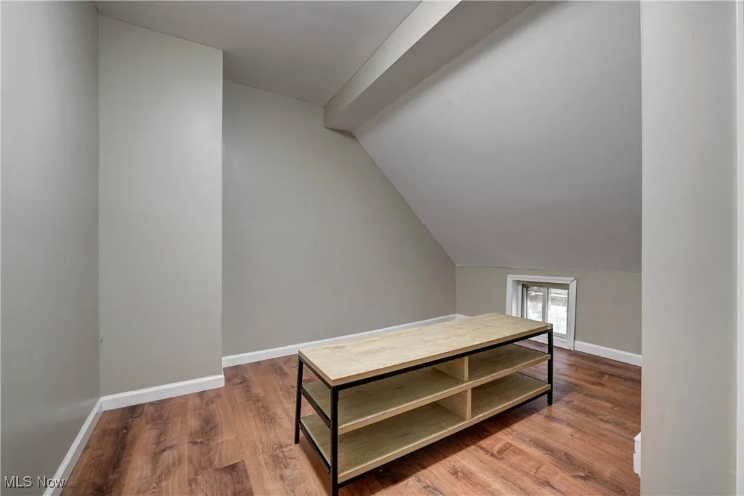 Additional living space featuring light wood-style flooring and vaulted ceiling