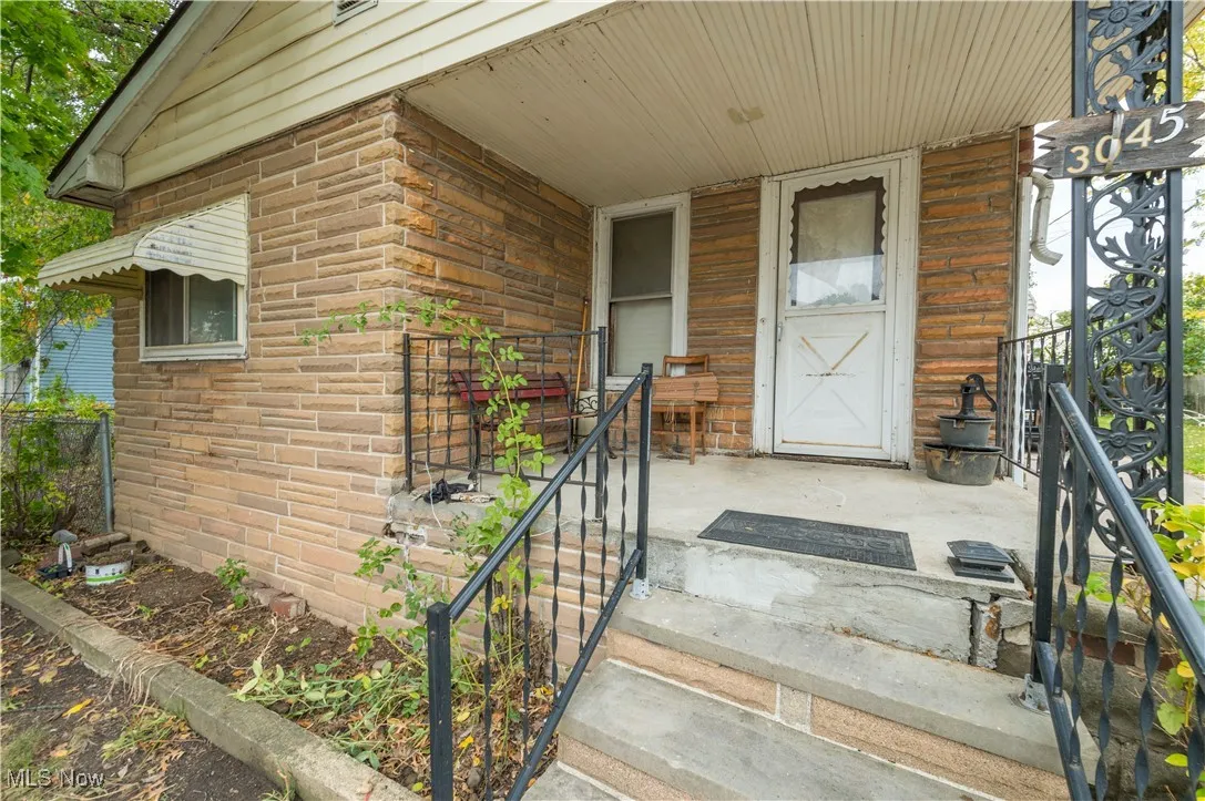 Doorway to property featuring brick siding and covered porch