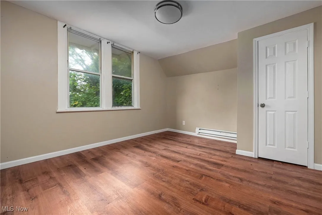 Bonus room featuring dark wood-style floors, baseboard heating, and vaulted ceiling