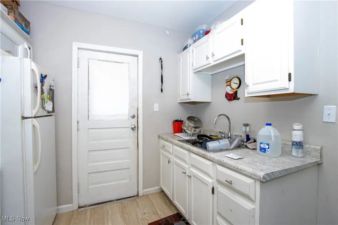 Kitchen with freestanding refrigerator, light countertops, white cabinetry, and light wood-style floors