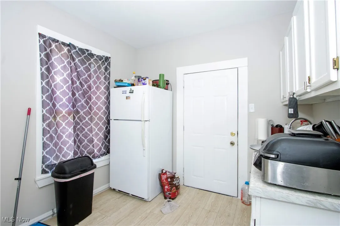 Kitchen with freestanding refrigerator, white cabinetry, light wood-style flooring, and light countertops
