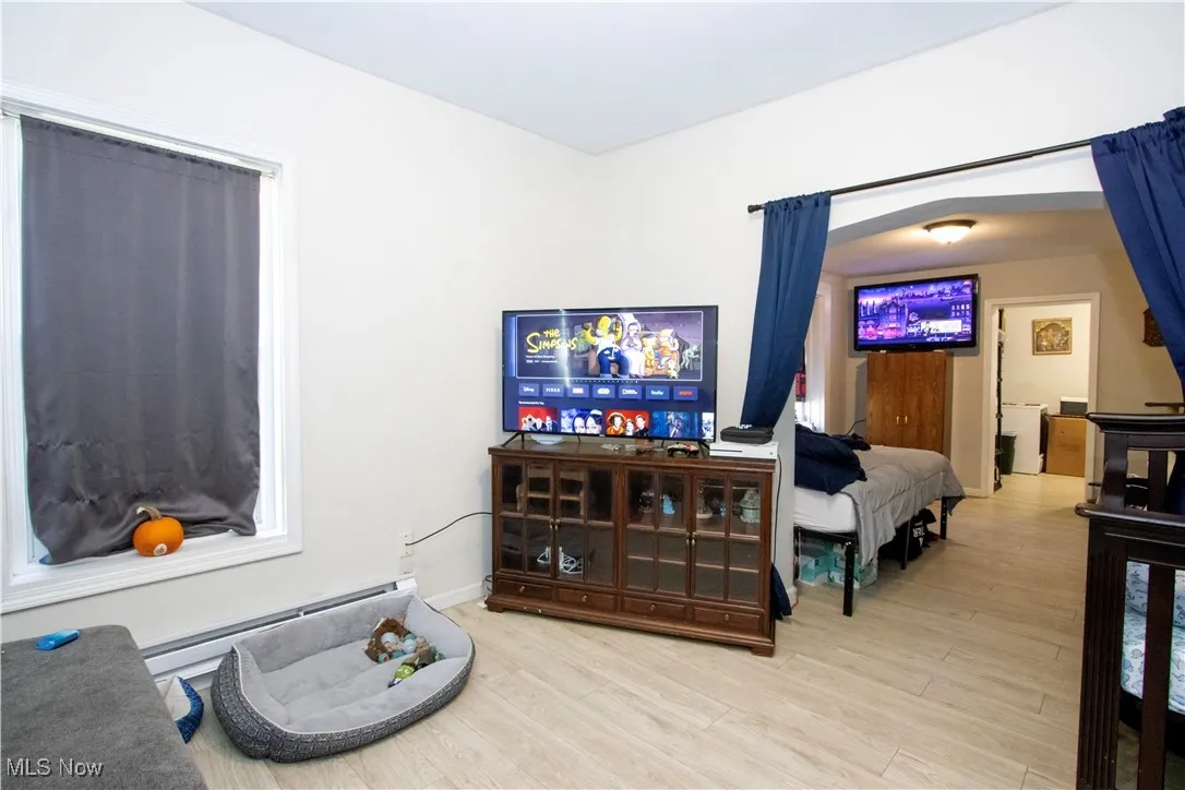 Bedroom with a baseboard heating unit and light wood finished floors