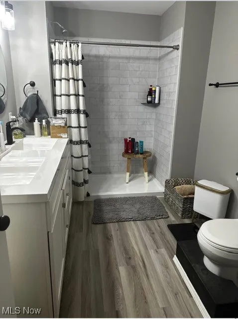 Full bathroom with vanity, a tile shower, and light wood-type flooring